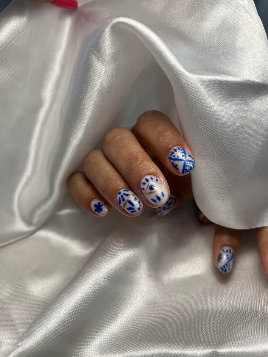 Manicura blanca con motivo de azulejo azul pintado a mano.