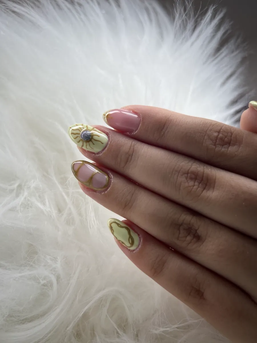 Manicura con detalles en pan de oro y verde sobre base nude.