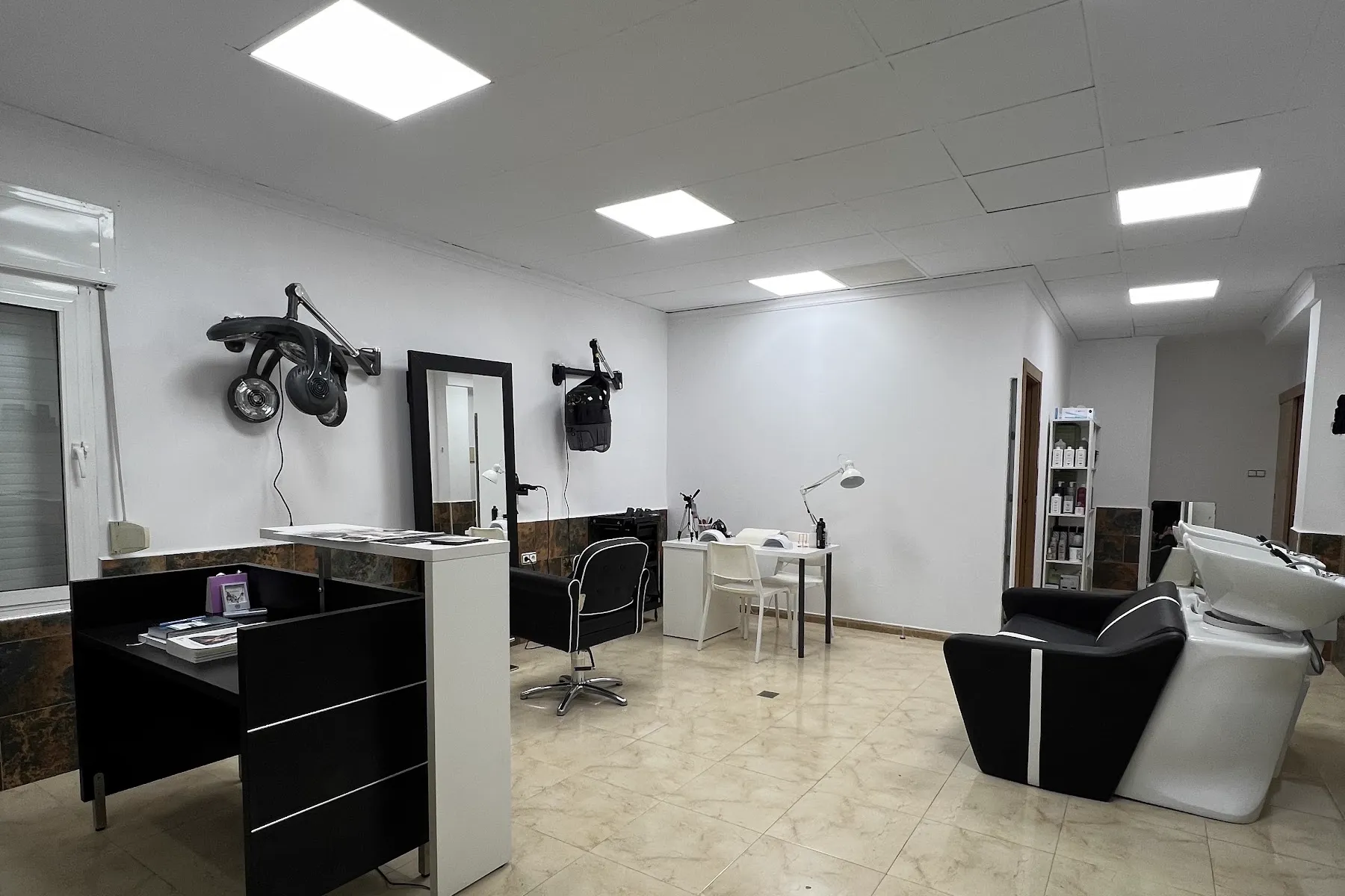 Interior del salón: puestos de peluquería, espejos y lavacabezas.